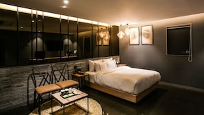 A modern bedroom with a large bed, a seating area with a table, and a large mirror. - Jeonju Mari Hotel Terminal Store (Jeonju)