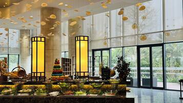 A spacious lobby with a marble reception desk, large windows, and hanging decorative elements.