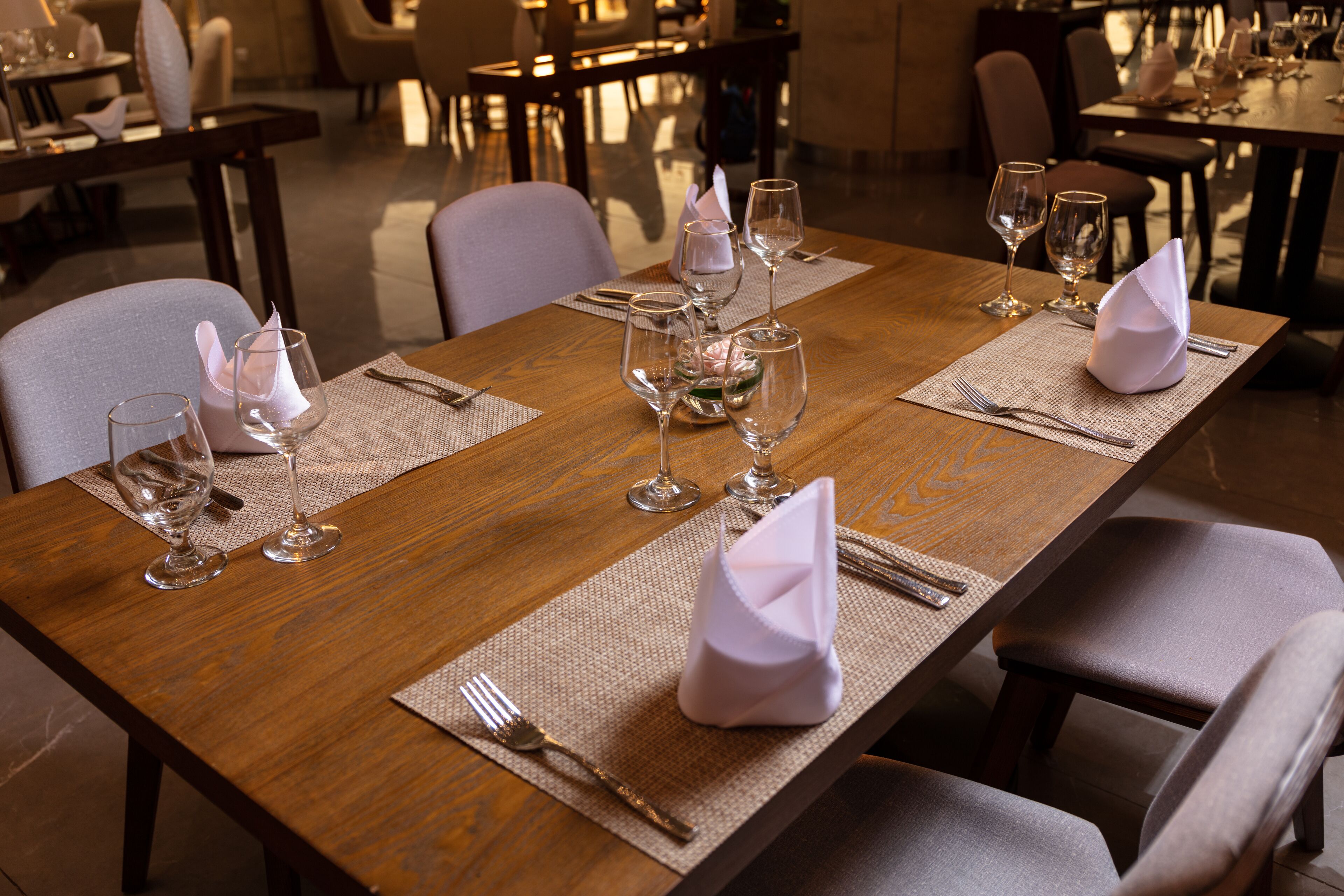 A dining table set with multiple wine glasses, napkins, and cutlery, indicating a formal dining arrangement.