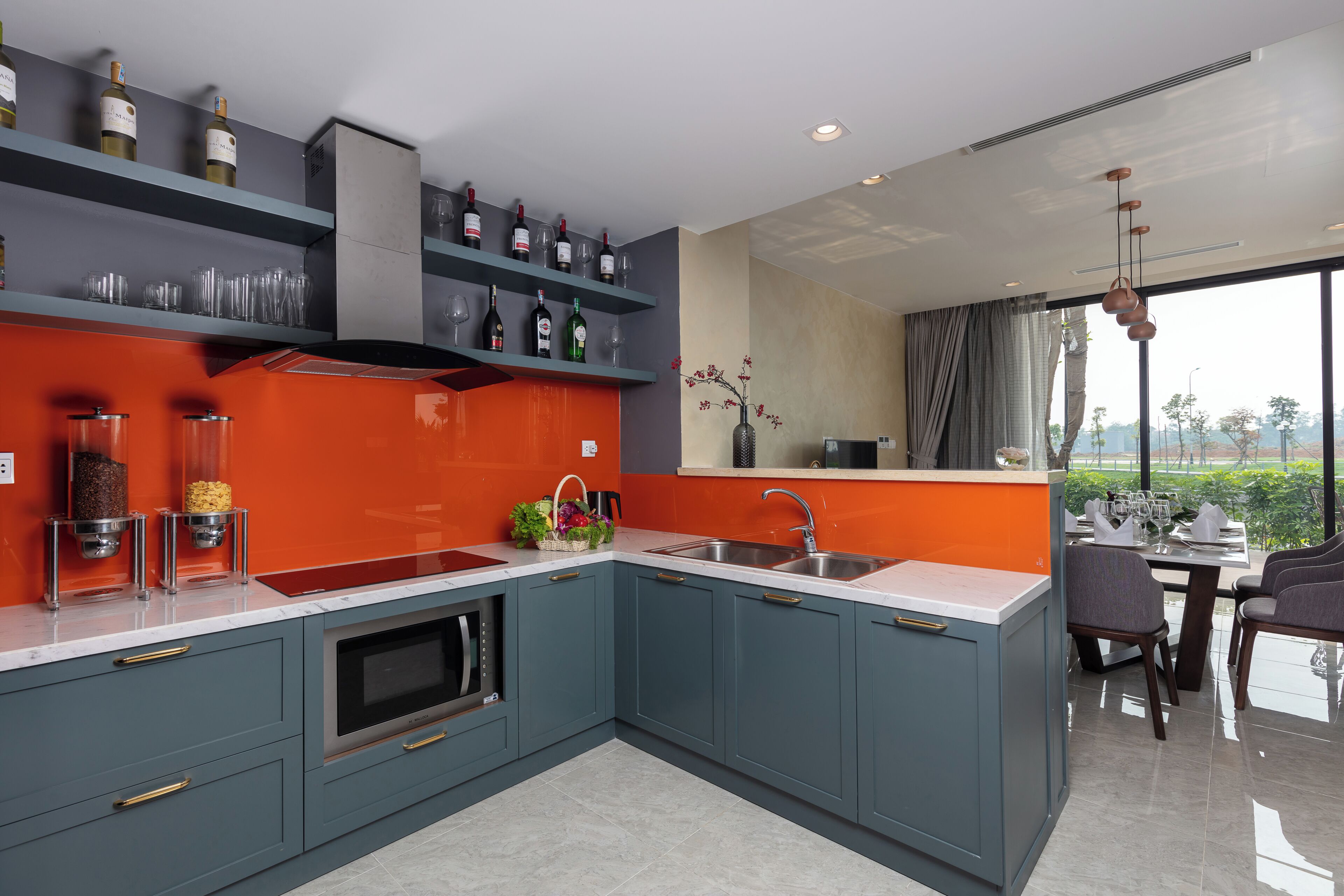Una cocina moderna con armarios grises, un salpicadero rojo y un comedor con vistas.