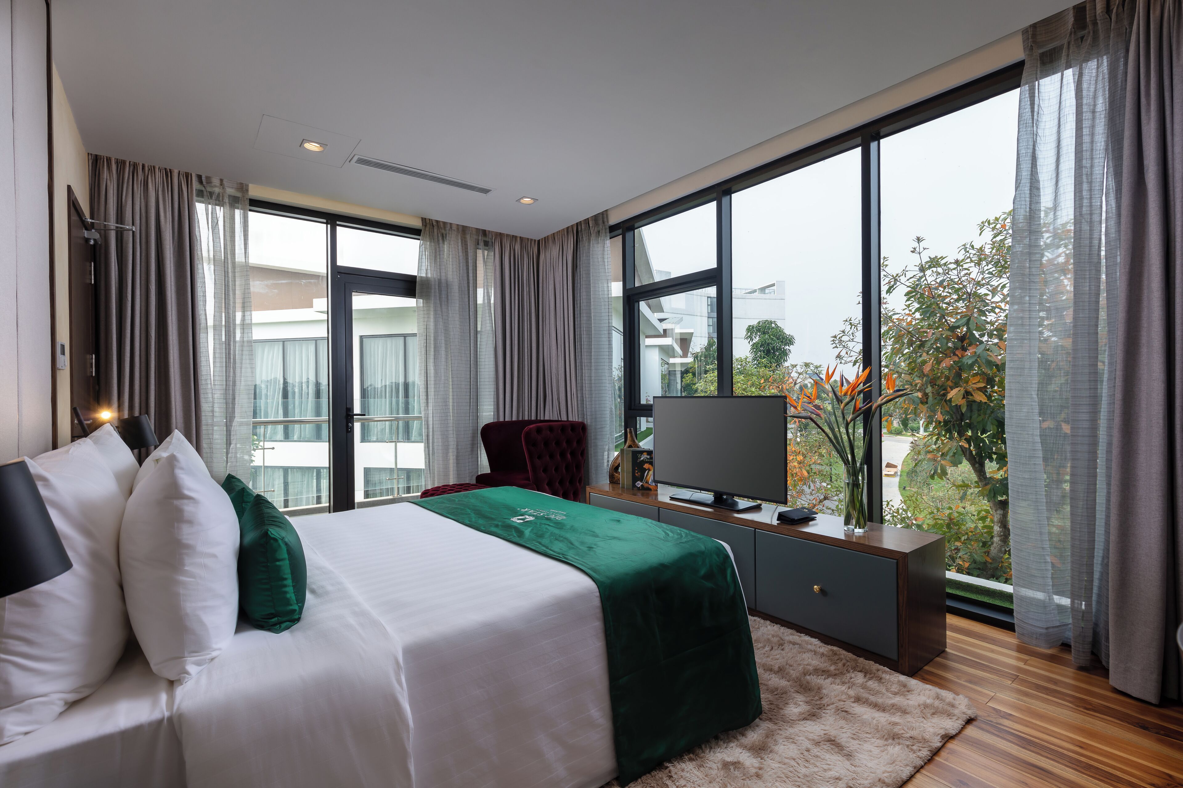 Una habitación de hotel moderna con una cama grande, televisión, escritorio y vistas a la ciudad.