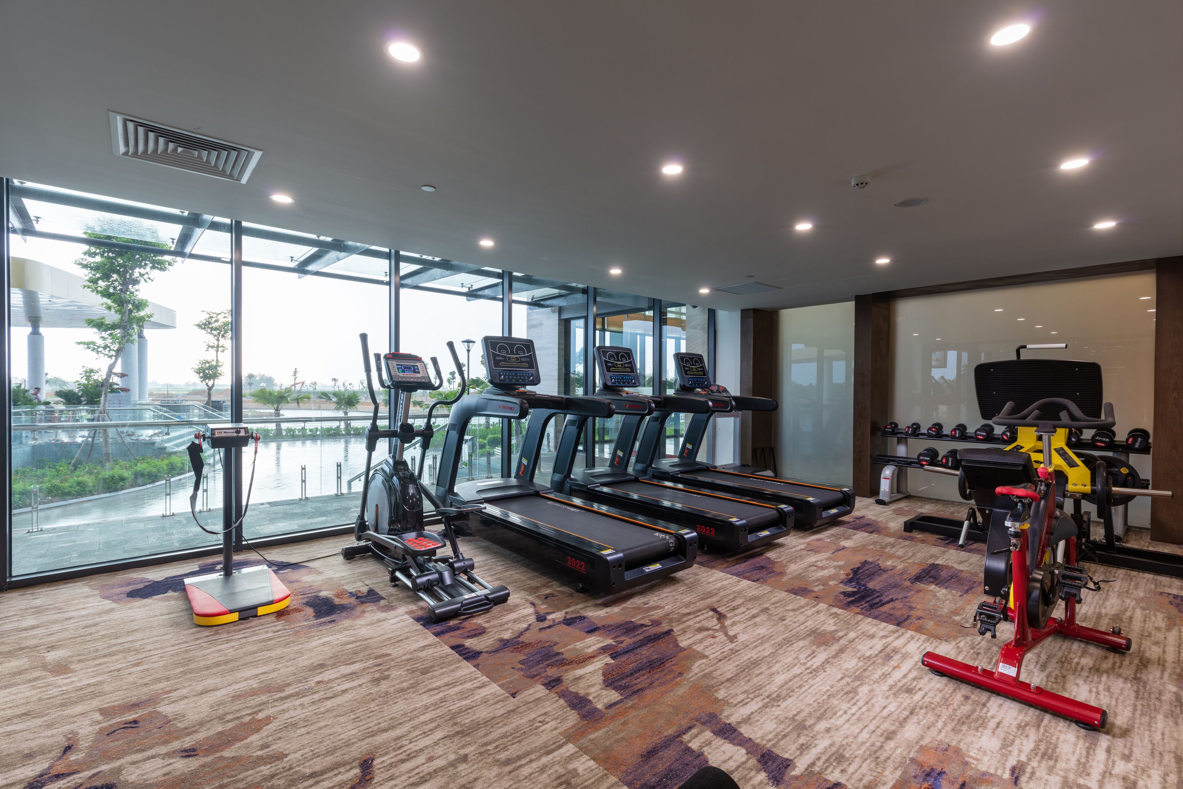 Een fitnessruimte met loopbanden, elliptische trainers en gewichthefrijsapparatuur.