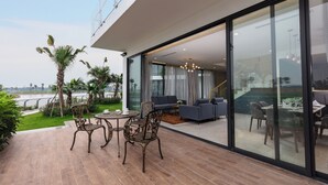 A modern outdoor patio with a dining set, a sofa, and a view of the interior. - DIC Star Hotels & Resorts Vinh Phuc (Vinh Yen)