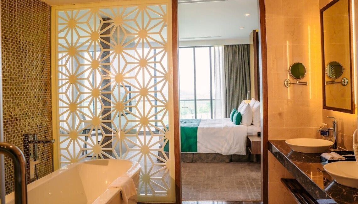 A hotel bathroom with a bathtub, two sinks, and a large mirror.