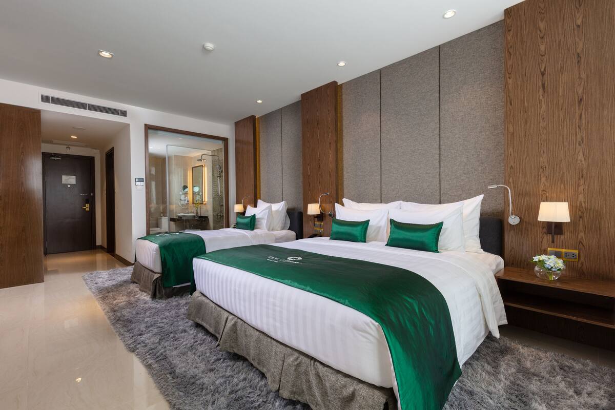 A modern hotel room with a large bed, two bedside tables, and a mirror.