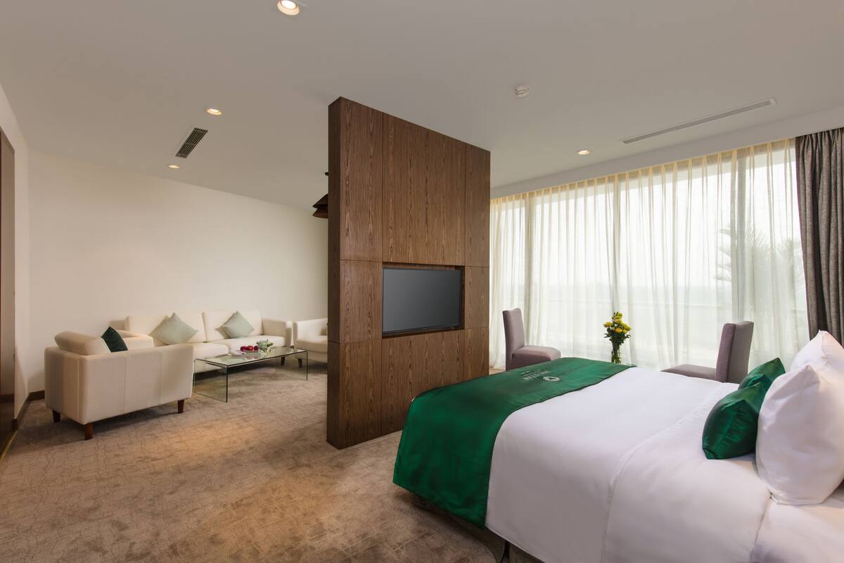 A hotel room with a bed, a sofa, a TV, and a coffee table.