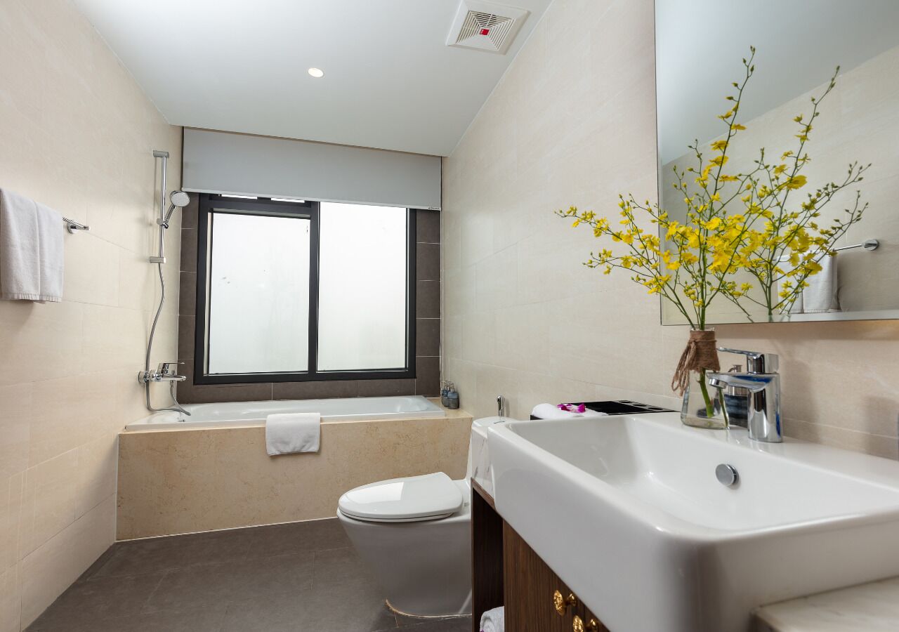 A modern bathroom with a bathtub, toilet, sink, and a window.