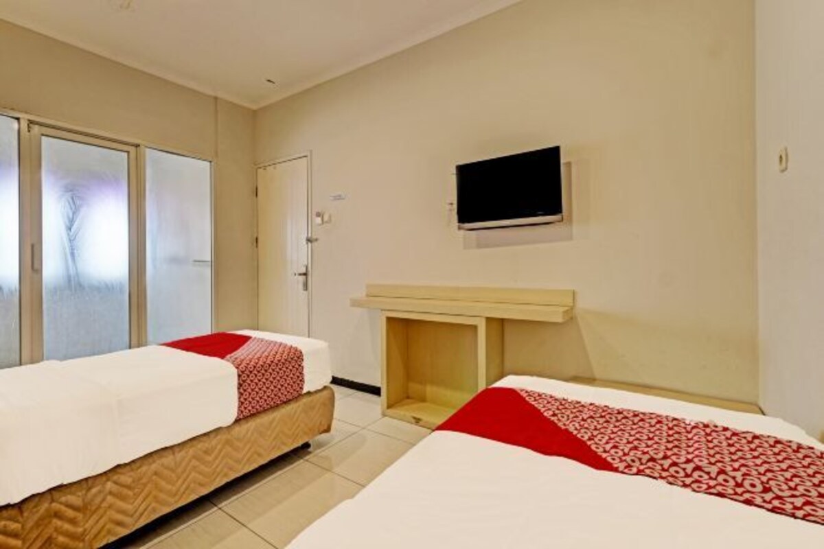 A hotel room with two beds, a television, and a small wooden table.