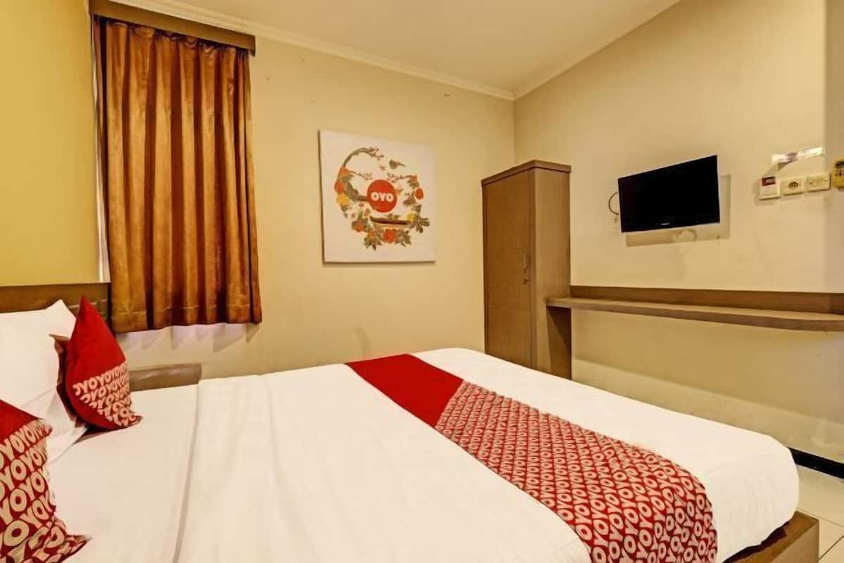 A hotel room with a bed, a television, a wardrobe, and a wall-mounted TV.