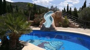 Una piscina con una formación rocosa y palmeras.