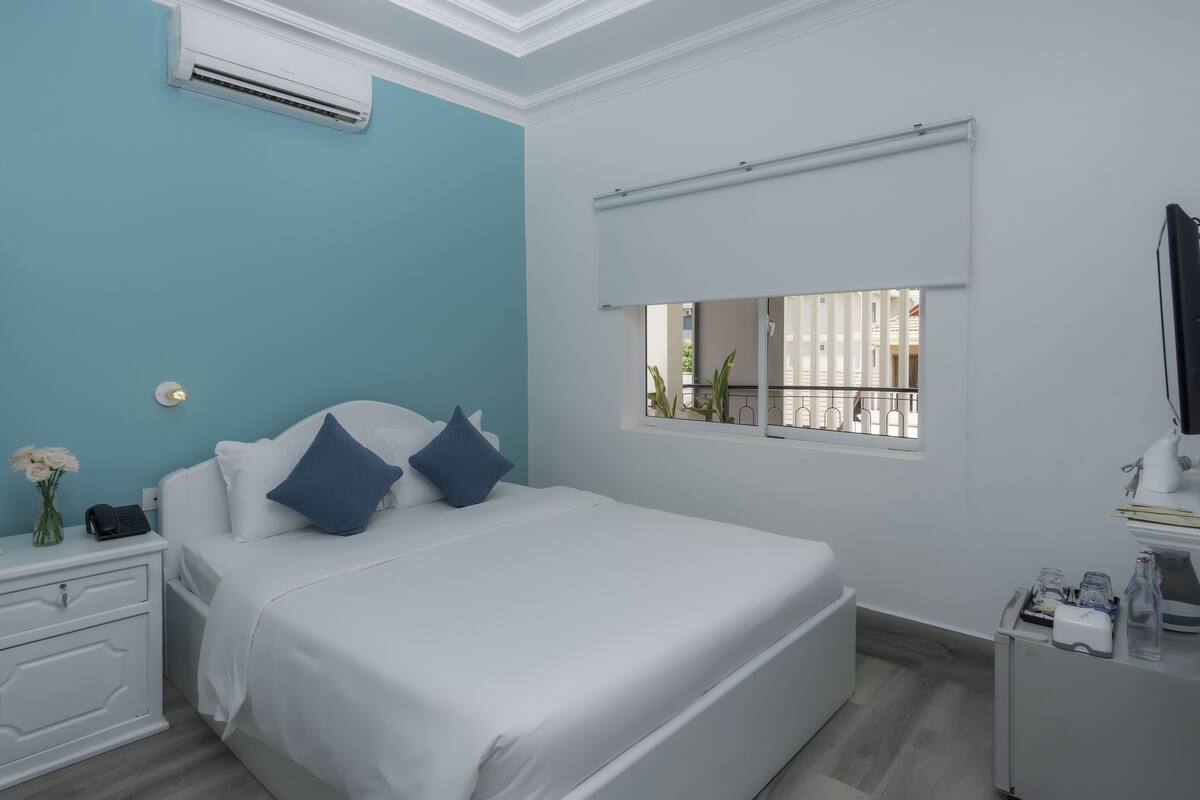 Ein Schlafzimmer mit Bett, Nachttisch und Fenster mit Aussicht.