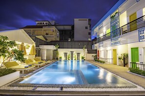 Una piscina al aire libre, sombrillas, sillones reclinables de piscina