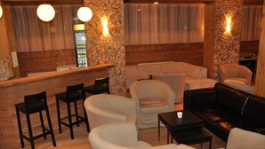 Un espace salon accueillant avec un mur en pierre, un plafond en bois et un comptoir de bar. Plusieurs options de sièges sont proposées, notamment des canapés et des fauteuils.