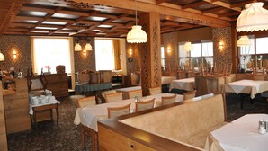Un restaurant avec des poutres en bois et des tables dressées pour le repas.