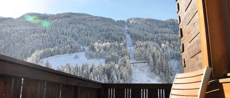 A wooden cabin with a balcony overlooking a snow-covered mountain.