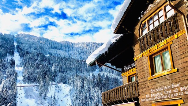 Un bâtiment en bois doté d’un balcon et d’une enseigne sur laquelle on peut lire « Saus Garaund ».