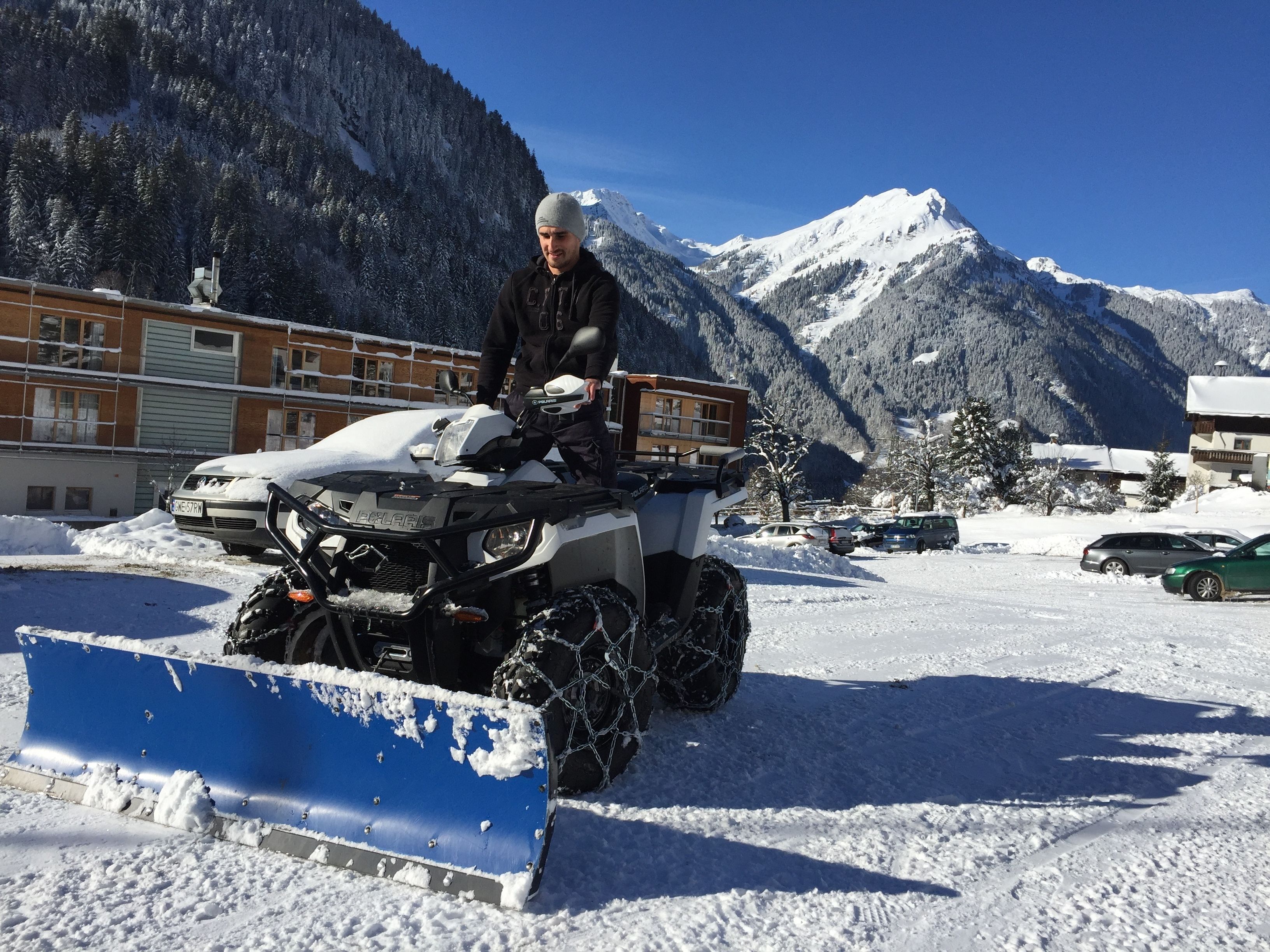 A person on an ATV in a snowy area with mountains in the background.