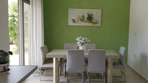 A dining area with a green wall, a wooden table, and six chairs. - Villa Marian (Apokoronas)