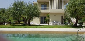 A modern building with a pool, surrounded by trees and a well-maintained lawn. - Villa Marian (Apokoronas)