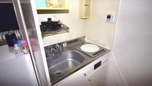 Una kitchenette compacta con un lavamanos, estufa y una pequeña encimera.