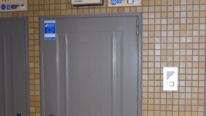 Habitación de hotel con dos puertas, un muro de azulejos y un termostato en la pared.