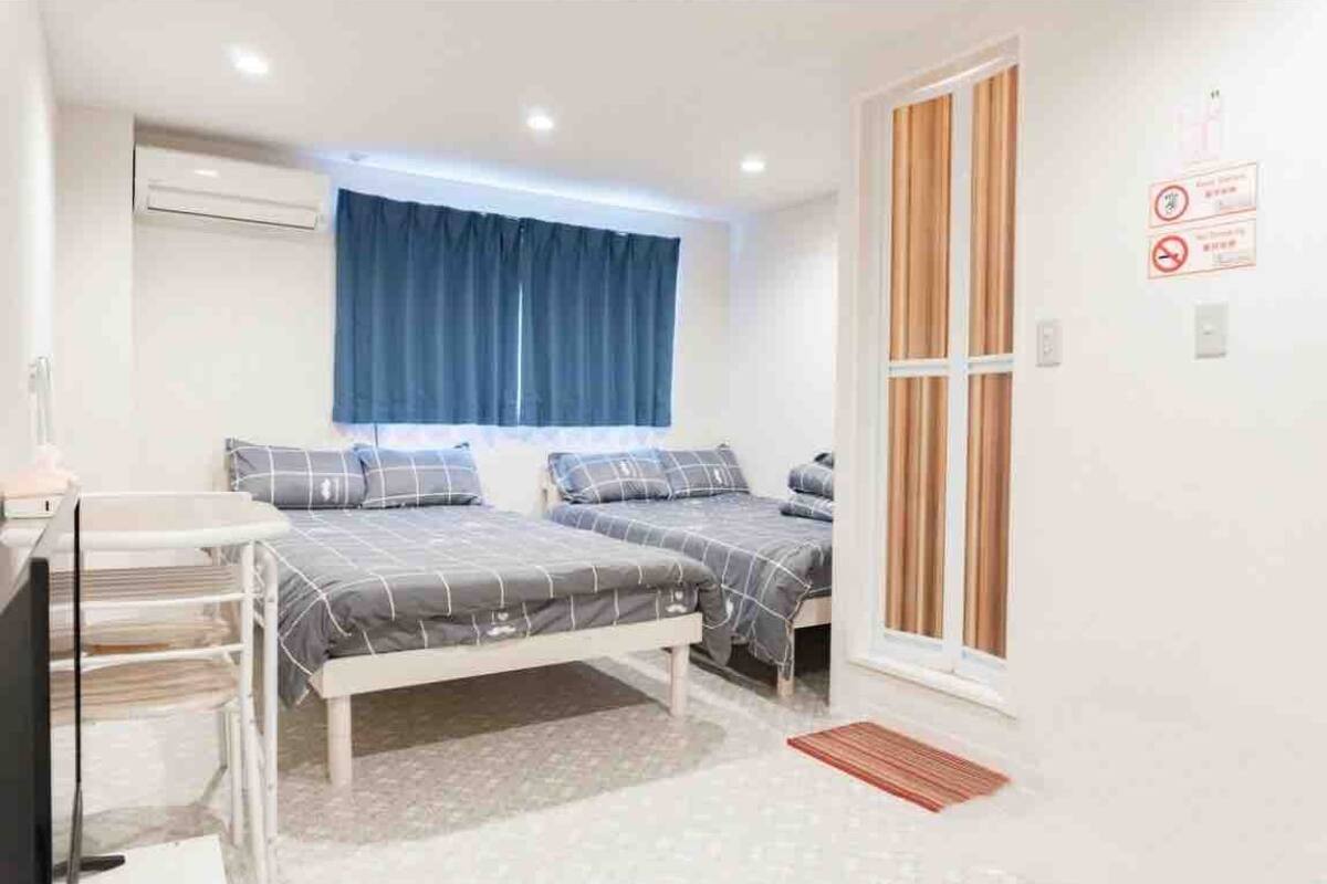 A bedroom with two beds, a desk, and a window with curtains.