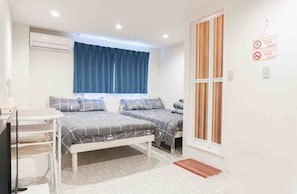 Quarto com duas camas, uma escrivaninha e uma janela com cortinas.