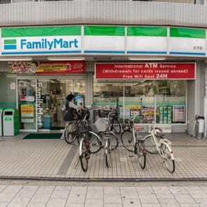 Uma loja FamilyMart com um aviso do Serviço de ATM Internacional, bicicletas estacionadas na frente e uma cobertura verde.