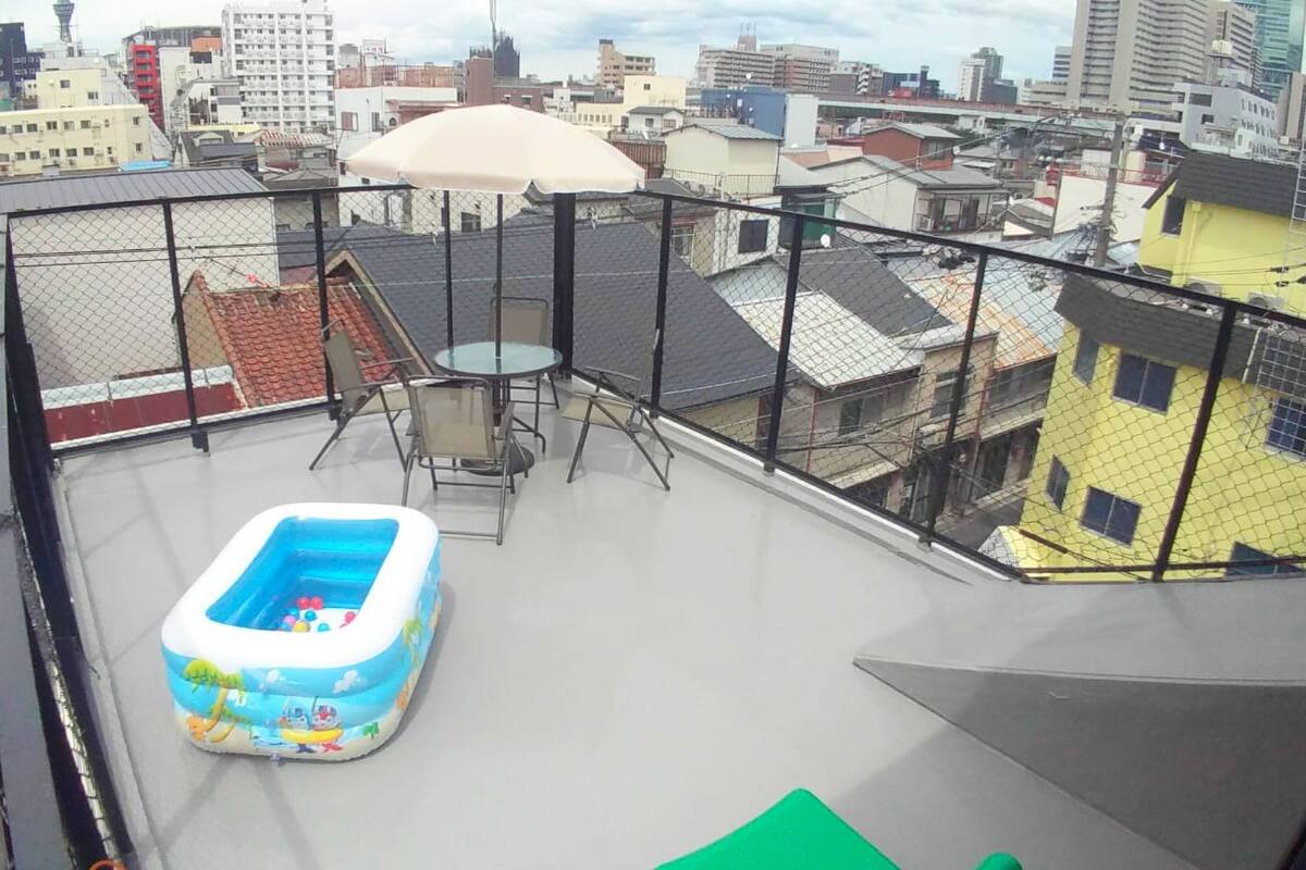 A rooftop with a small inflatable pool, a table, and a chair.