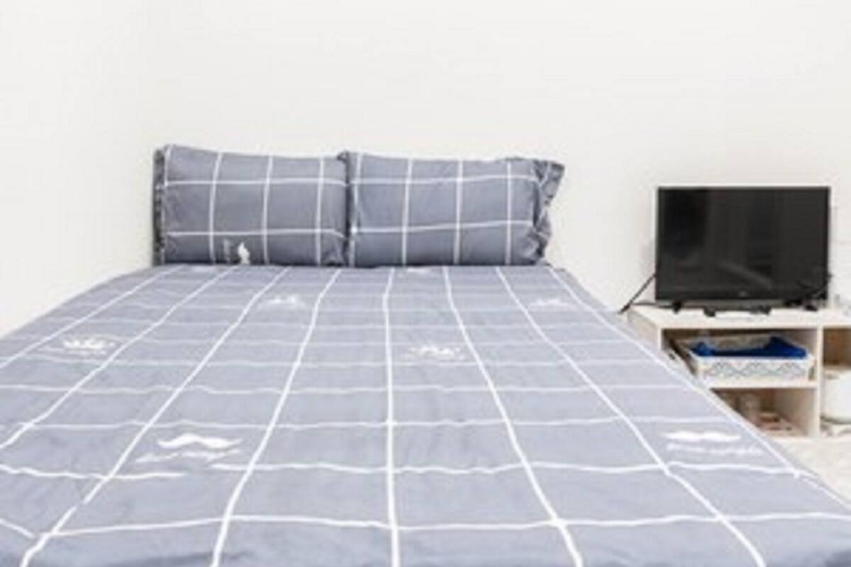 A bedroom with a bed, pillows, a TV, and a shelf.