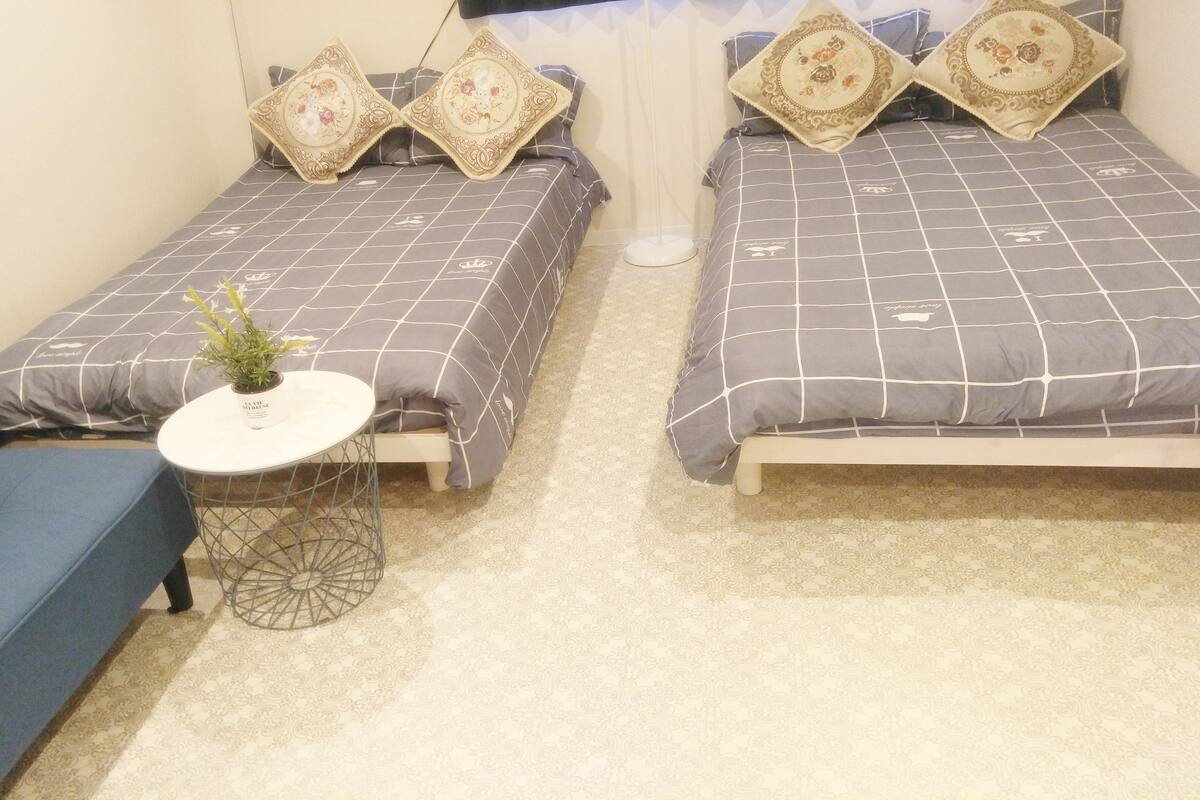 A bedroom with two single beds, a small round table with a plant, and a blue sofa.