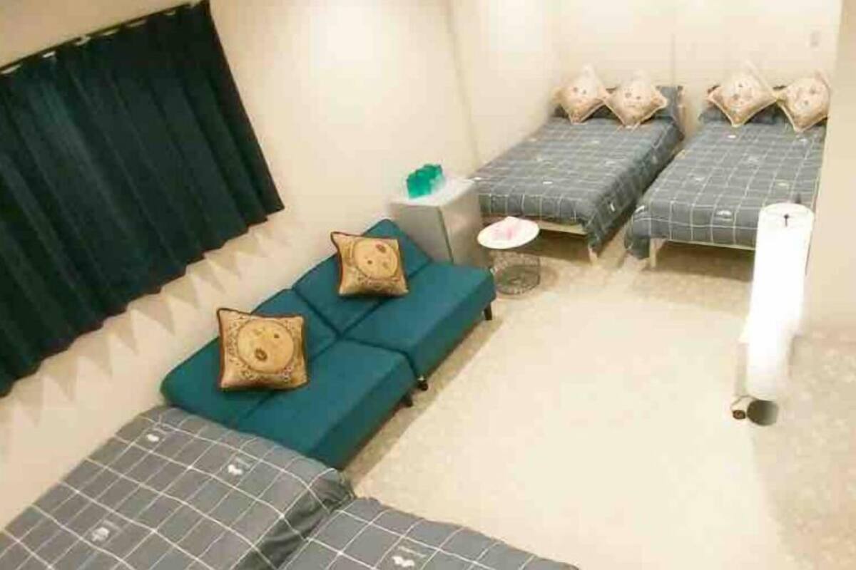 A room with two beds, a blue sofa, and a small round table.