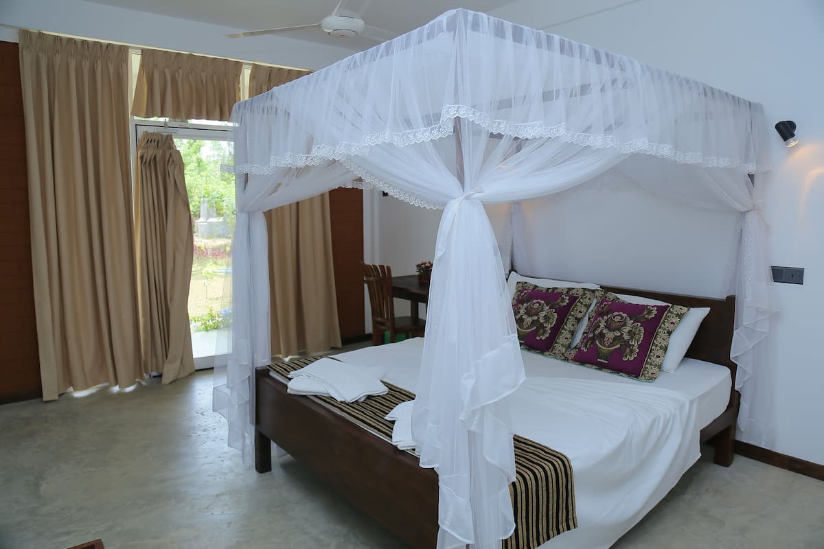Quarto com cama de dossel, ventoinha no teto e vista para o exterior.