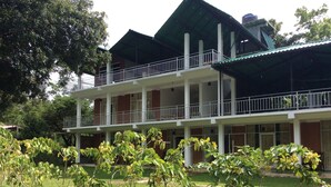 Un edificio de dos plantas con techo verde y barandillas blancas.
