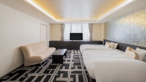 Une chambre d’hôtel avec un canapé, deux lits, une télévision et une moquette à motifs.