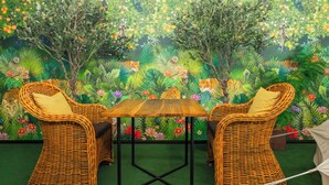 Une pièce meublée de meubles en osier, avec une table en bois et une fresque représentant une scène de jungle.