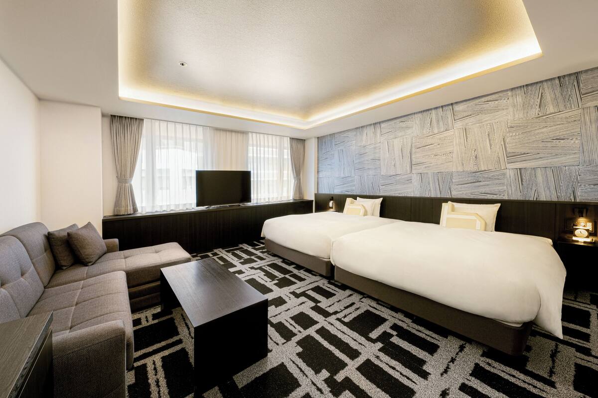 Een moderne hotelkamer met een bank, een groot bed, een flatscreen-tv en een kamerkleed met dessin.