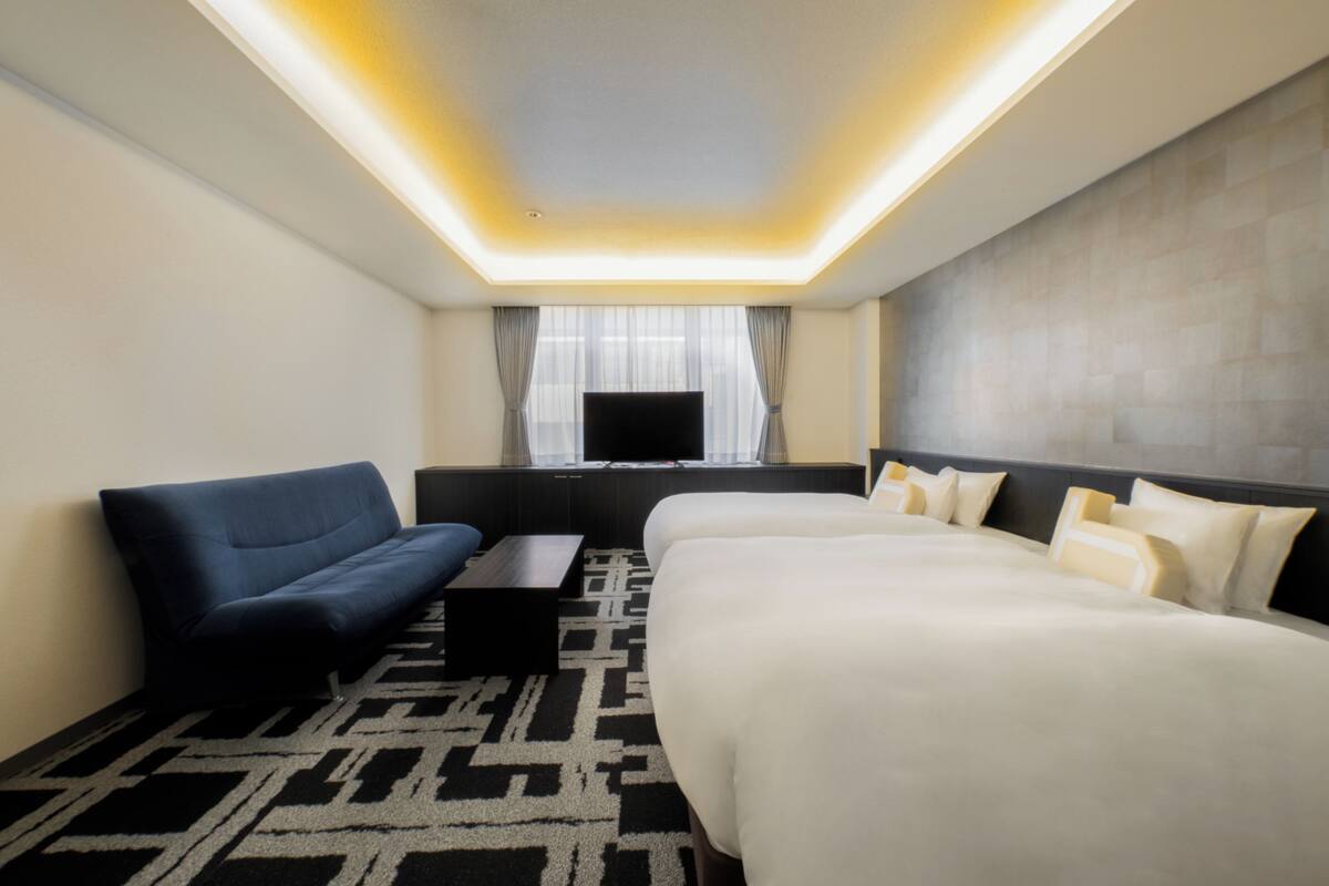 Een hotelkamer met een groot bed, een bank, een televisie en een kamerbreed tapijt met een patroon.