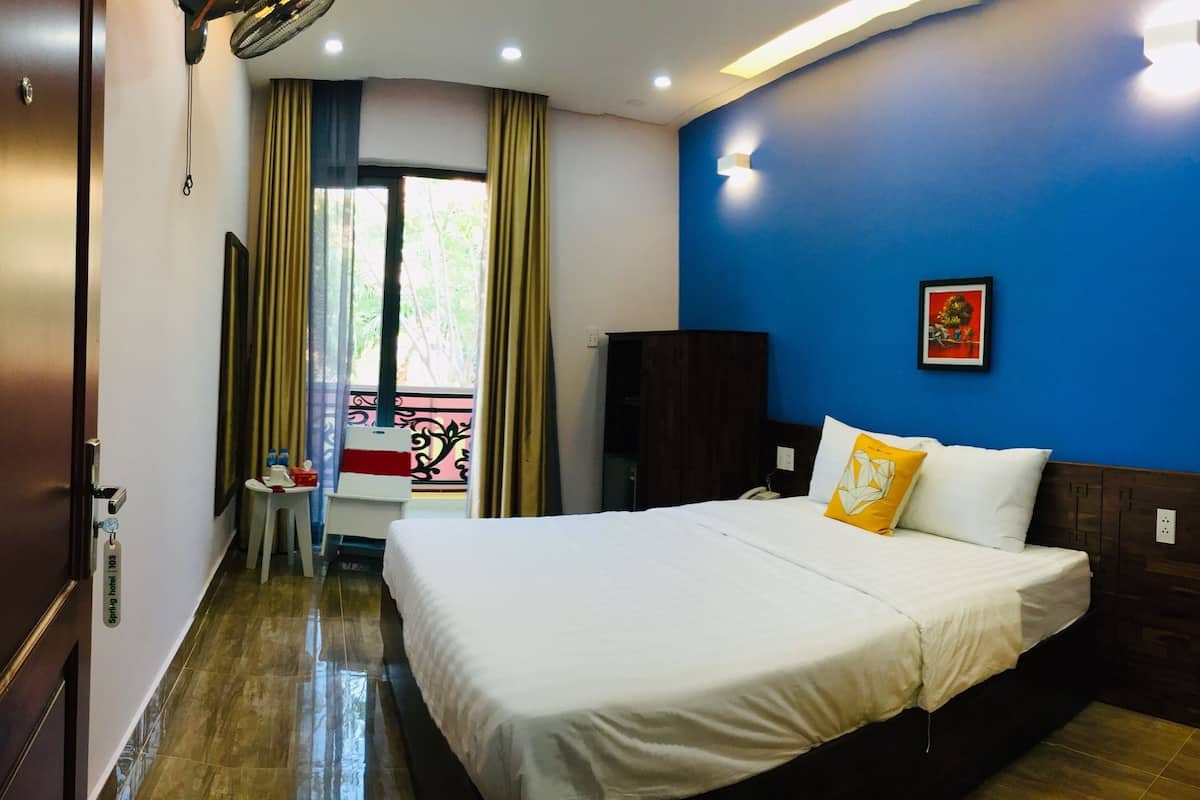 A hotel room with a bed, a desk, a chair, and a window with curtains.