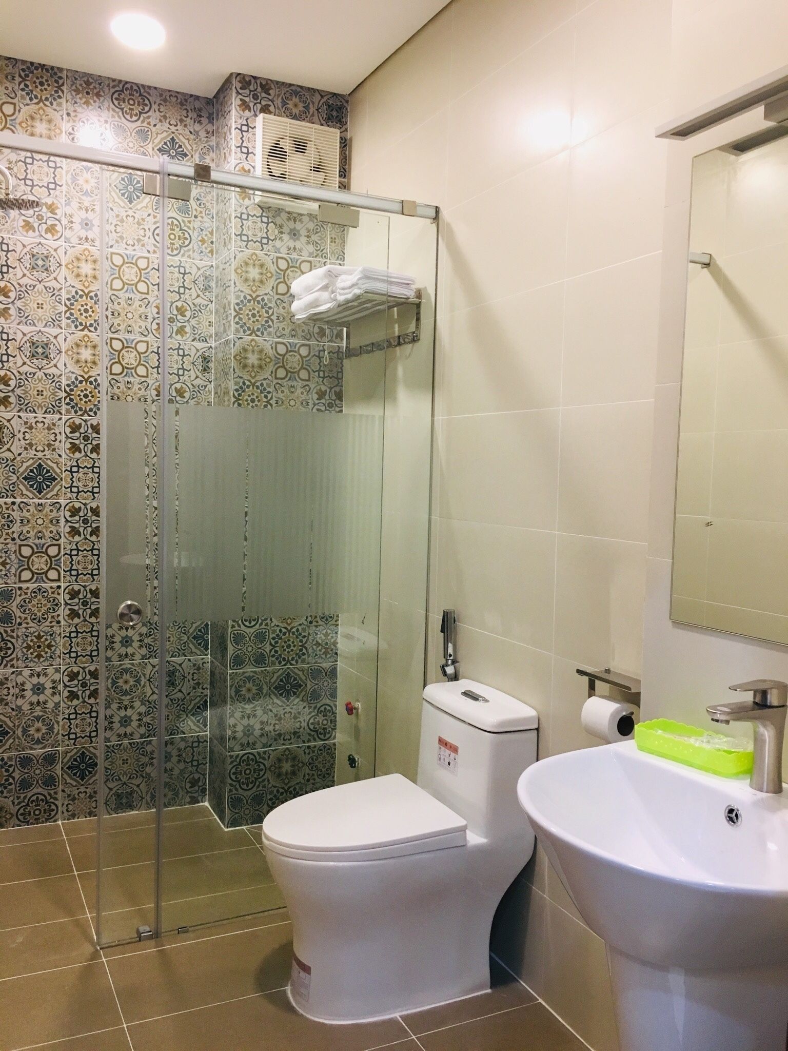 A bathroom with a shower enclosure, toilet, sink, and a mirror.