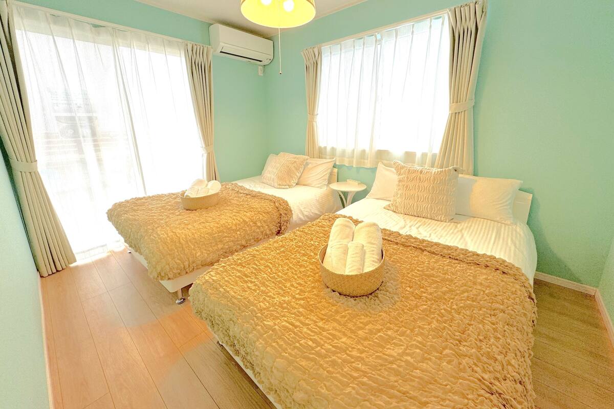 Une chambre d’hôtel avec deux lits, une petite table et un ventilateur de plafond.