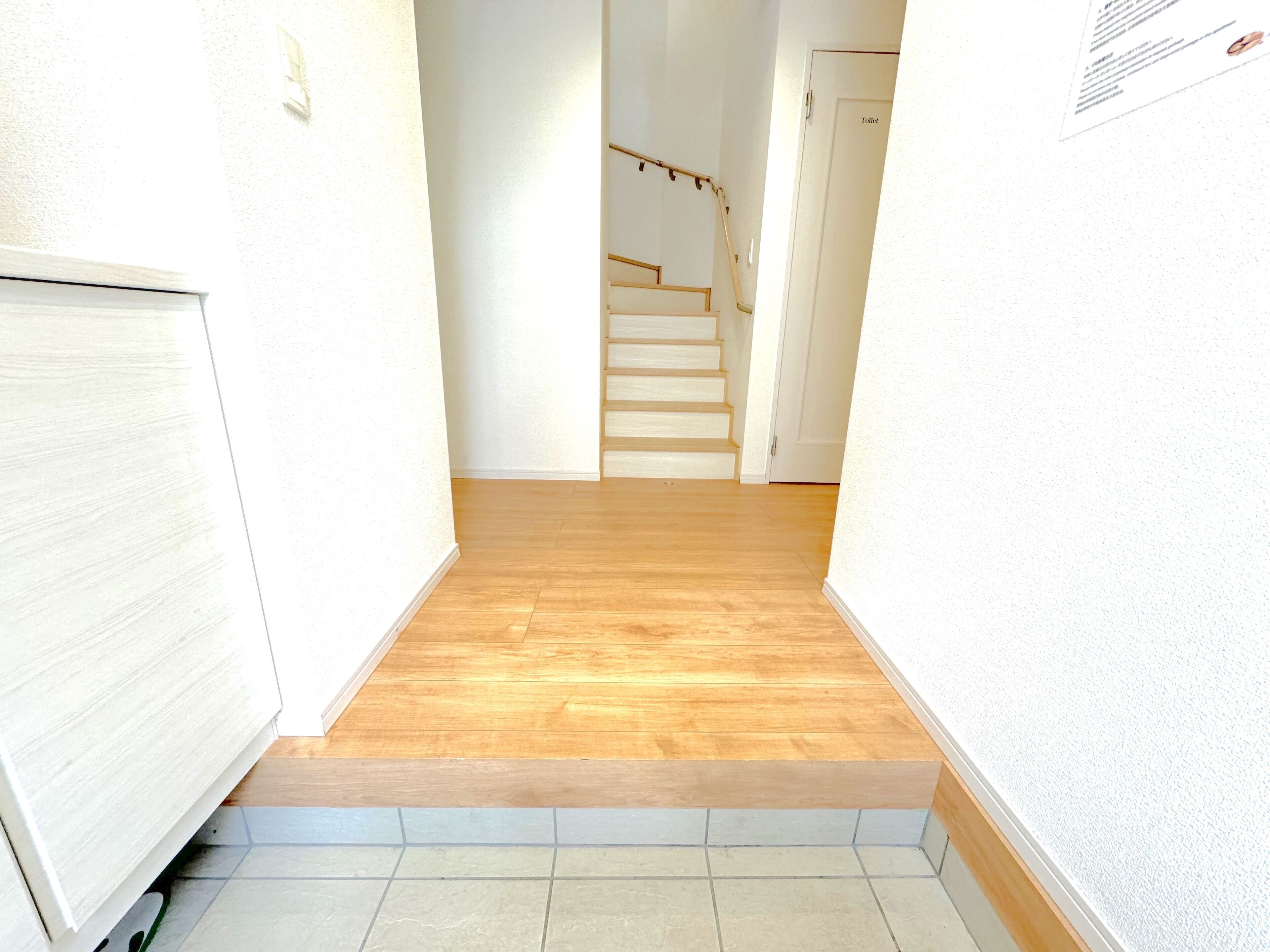 A narrow hallway with wooden flooring leading to a staircase.