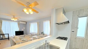 A modern kitchen with a central island, stainless steel sink, and a gas stove. - Grandioso Okinawa Villa Onna 2 (Onna)