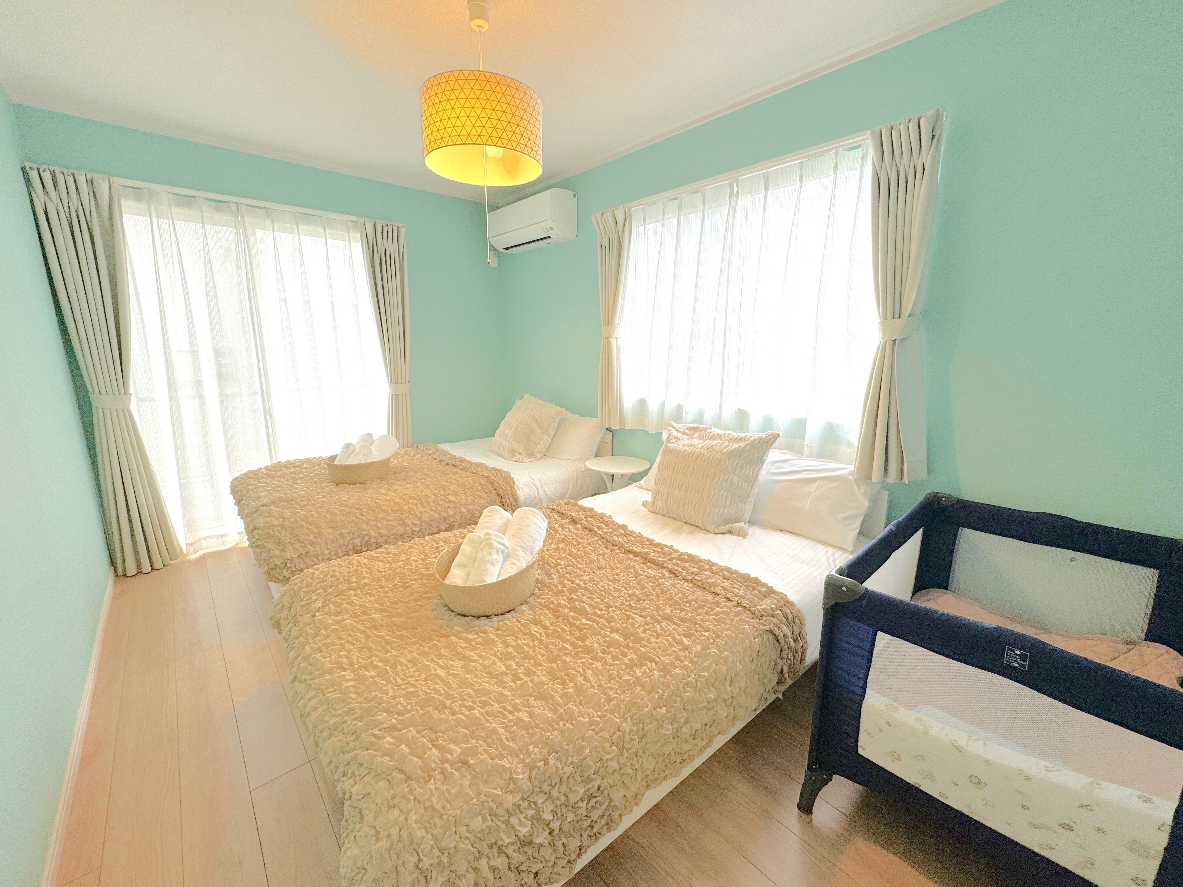 A room with two beds, a small table, and a crib.