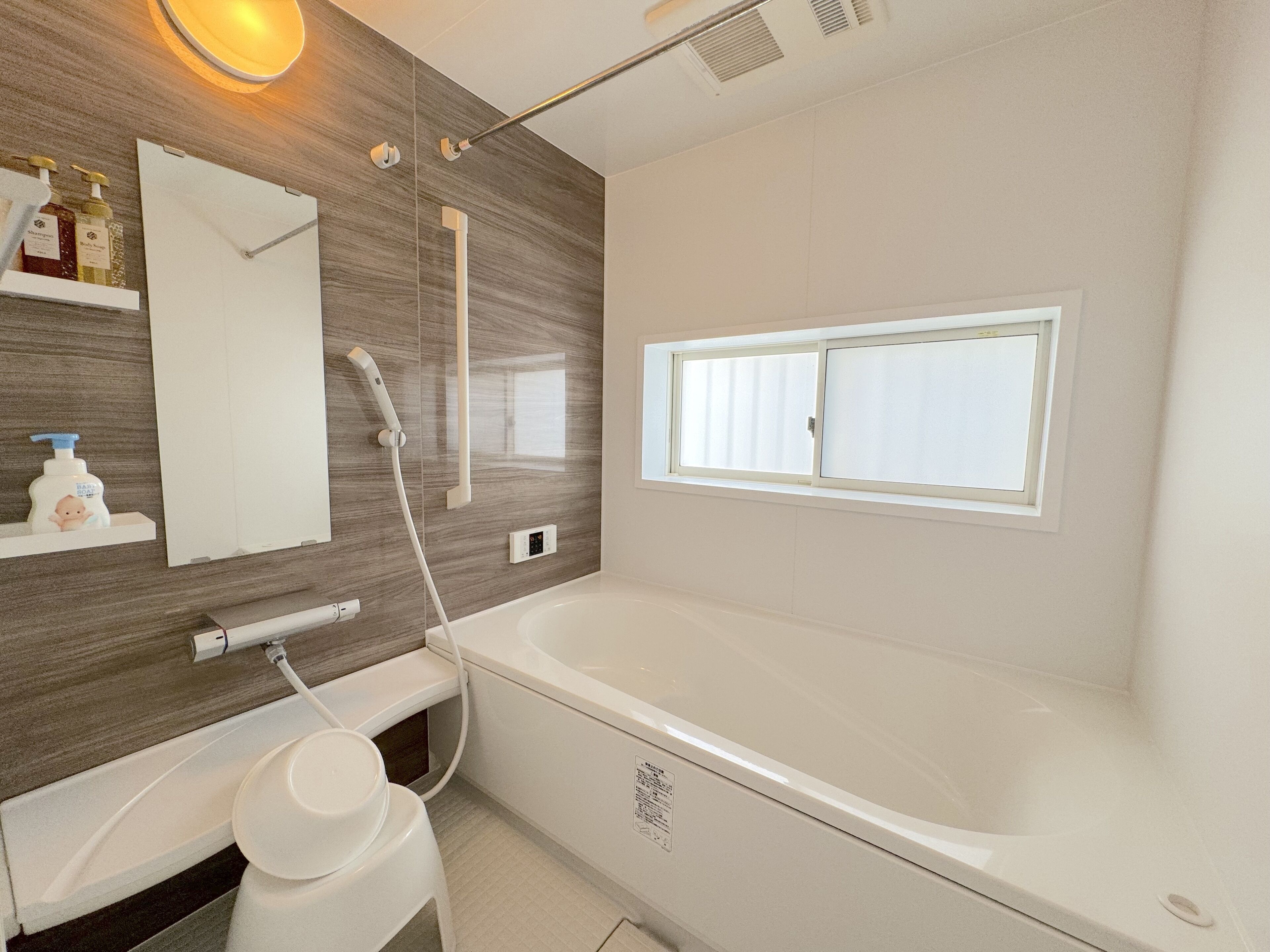 A modern bathroom with a large bathtub, a shower, a vanity with a mirror, and a window providing natural light.