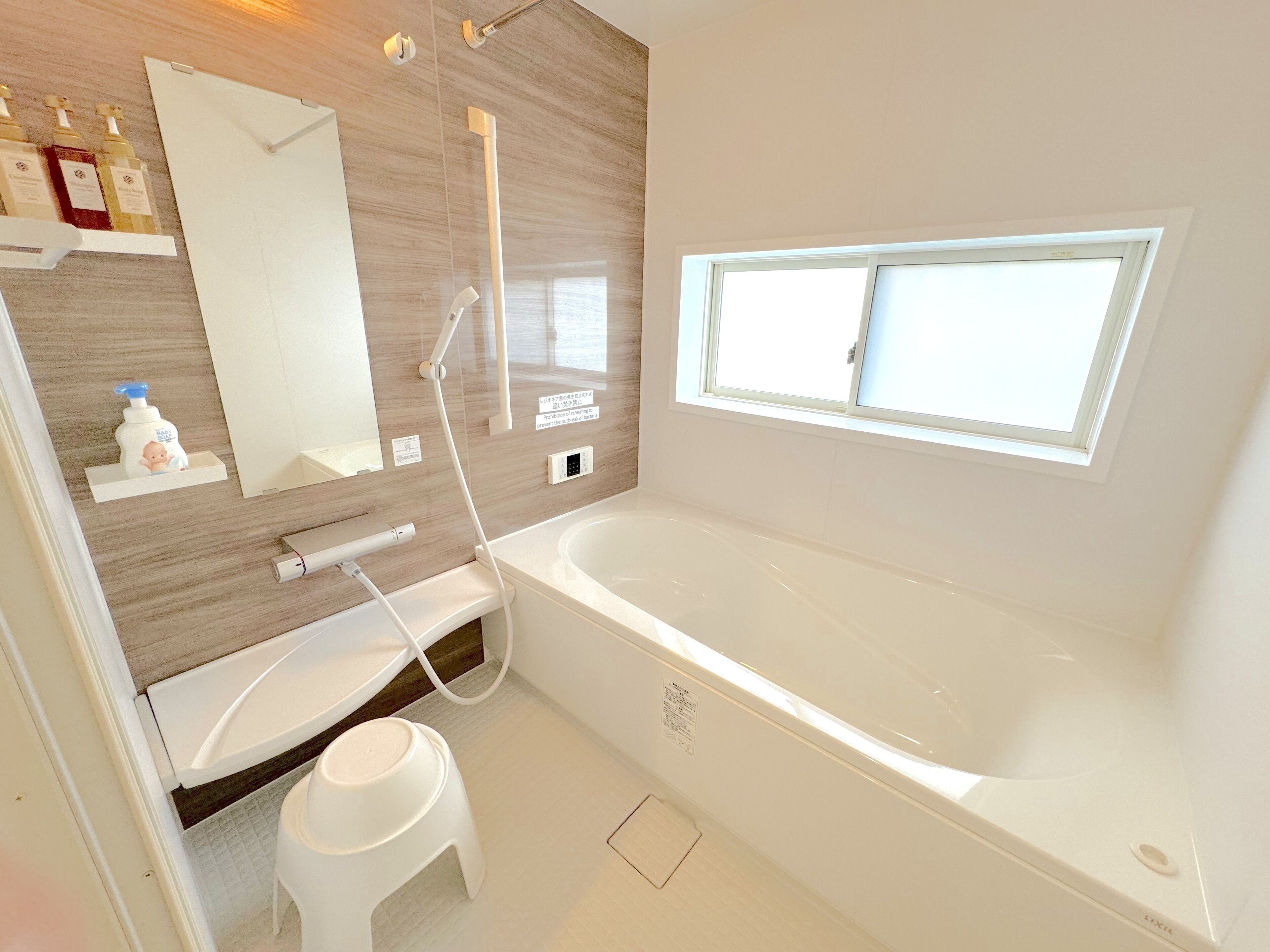 A modern bathroom with a large bathtub, a vanity with a mirror, and a window providing natural light.