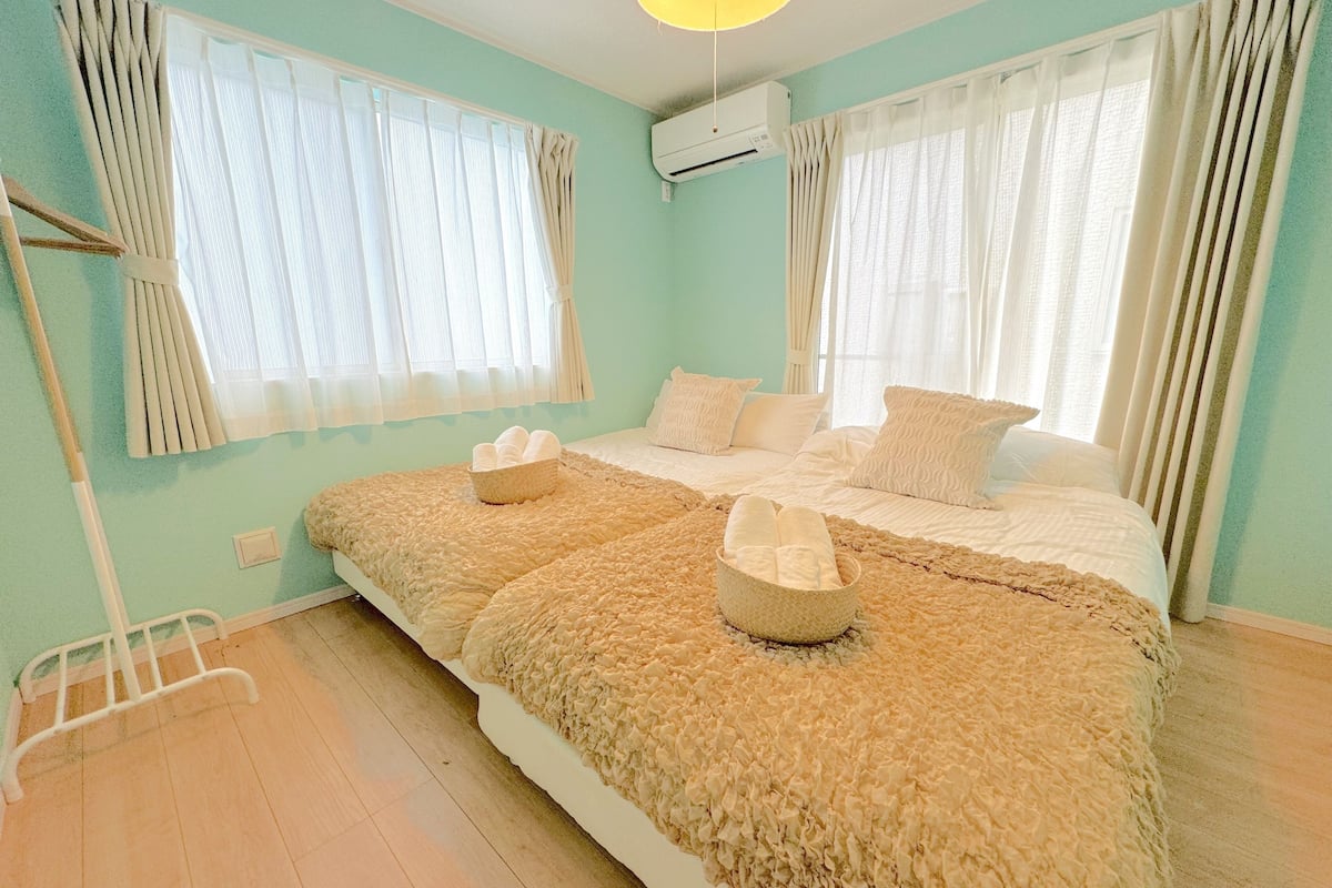 Une chambre à coucher avec un grand lit, deux tables de chevet et une fenêtre avec des rideaux.