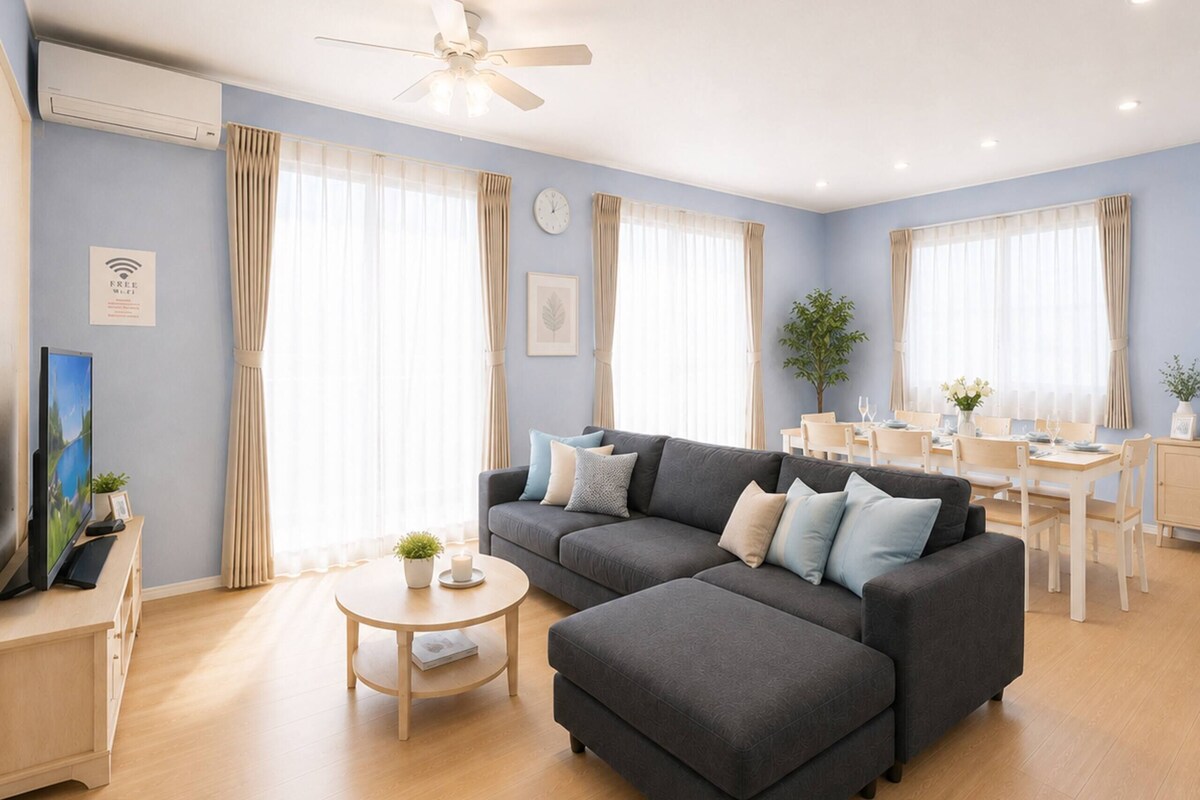 Una sala de estar moderna con un sofá gris, una mesita redonda y una zona de comedor con una mesa y sillas de madera.