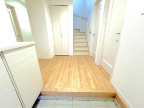 Ein schmaler Flur mit Holzdielen, weißen Wänden und einer Treppe zu einer anderen Etage.