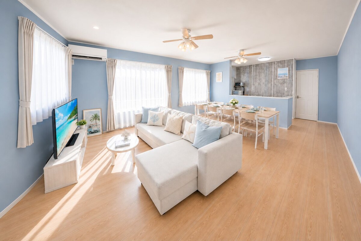 Una sala moderna con sofá, televisión y comedor.